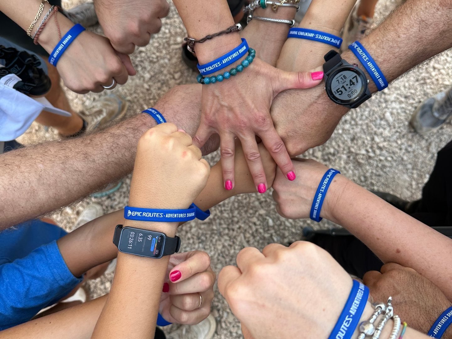Diventare Epic Router: i polsi del gruppo con i braccialetti Epic Routes uniti al centro, durante il trekking all'alba a Punta Palascia
