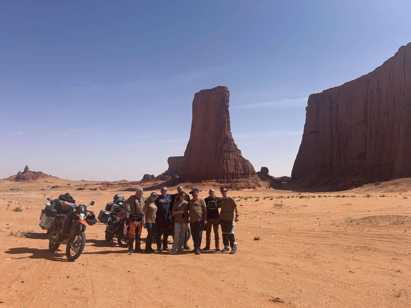 Motoviaggiatori in posa davanti alle torri di roccia del deserto di Brezina, in Algeria