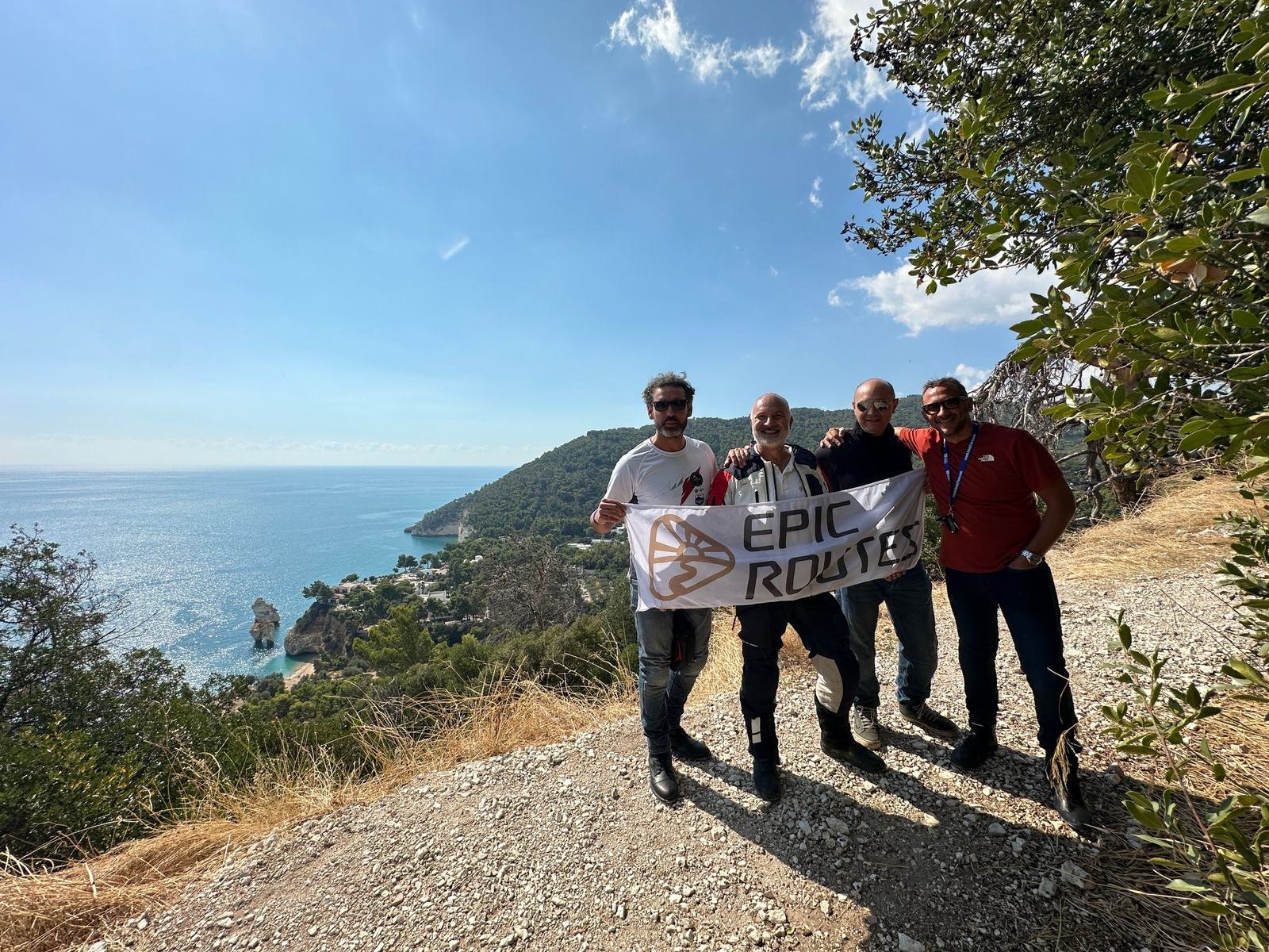 Il gruppo Motoraid di Epic Routes Community con lo striscione sopra la Baia delle Zagare, nel Gargano