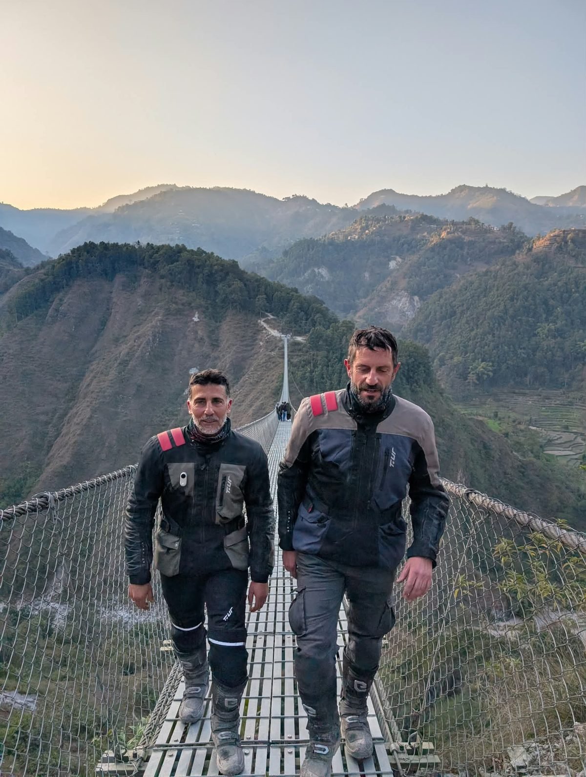 Gianni Fersini e Salvatore D'Emilio in tenuta da moto su un ponte sospeso lungo la Siddhartha Highway, verso Pokhara, in Nepal