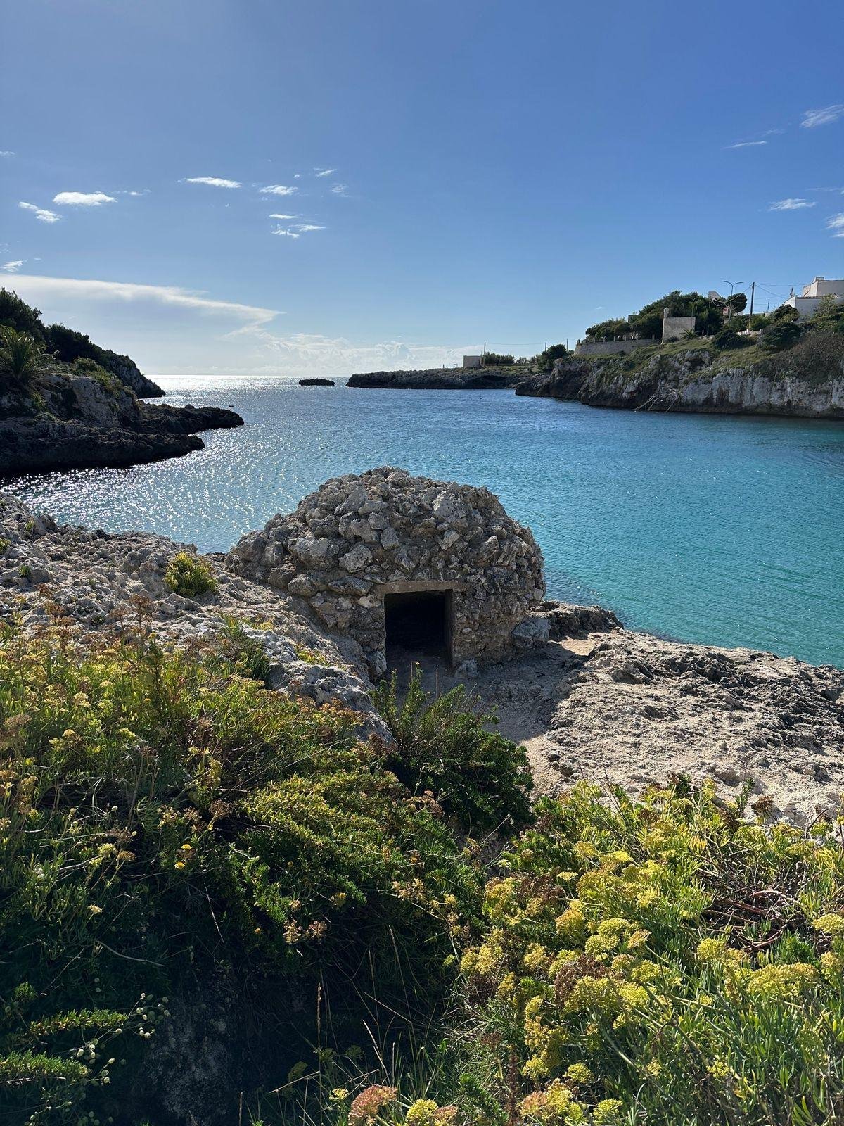 L'insenatura di Porto Badisco con l'acqua turchese e un antico ricovero in pietra sulla scogliera