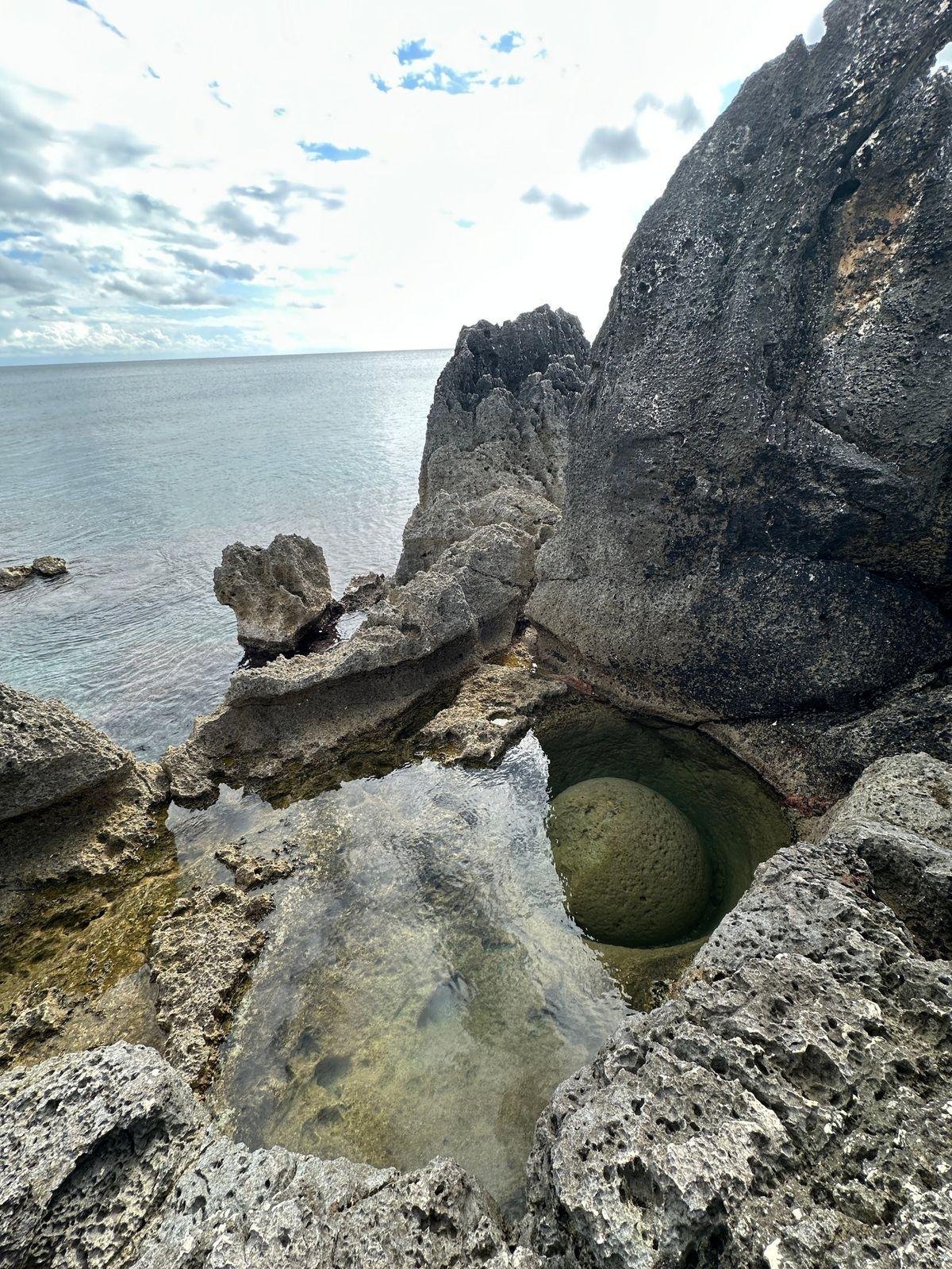 Una pietra tonda levigata dal mare dentro una pozza d'acqua limpida tra gli scogli del Salento