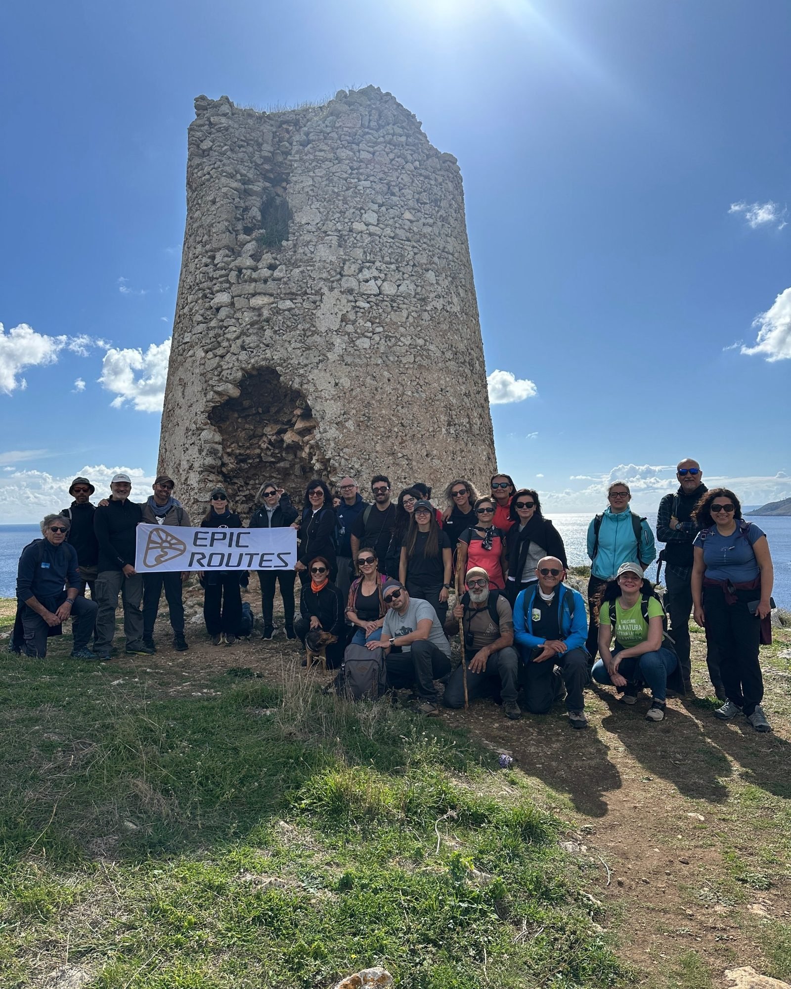 Gruppo di escursionisti di Epic Routes Community con lo striscione davanti a Torre Sant'Emiliano, sulla costa di Porto Badisco nel Salento