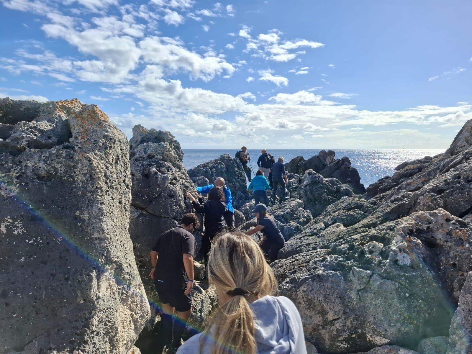 Escursionisti di Epic Routes Community si muovono tra gli scogli della costa salentina, con il mare davanti